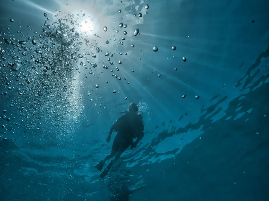 Dos buceadores ascendiendo hacia la luz del sol en Koh Tao