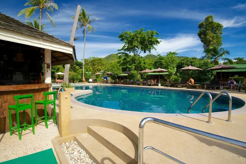 Swim-up pool bar with green stools